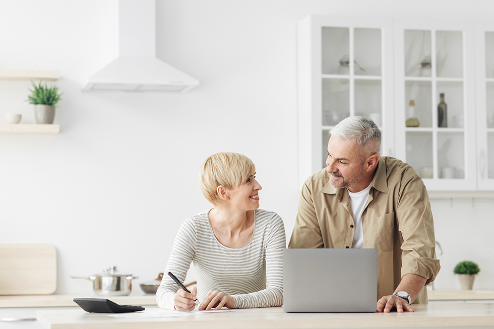 A couple in their kitchen looking online at the Absolute Best Insurance website for Medicare plans | Medicare Expenses In Boca Raton