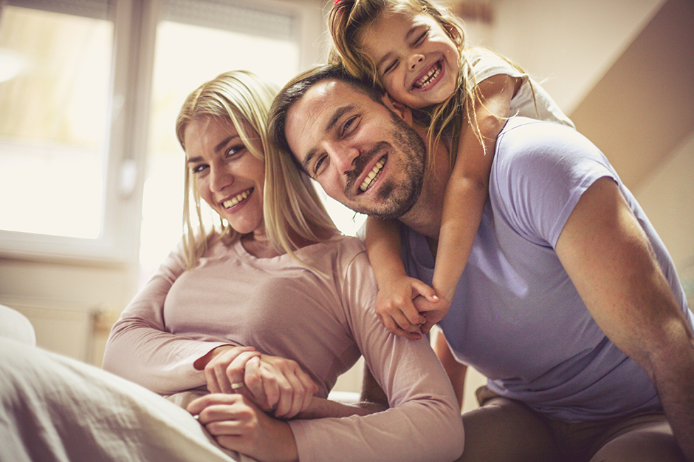 Young family hugging and smiling at home | ACA Insurance Coverage