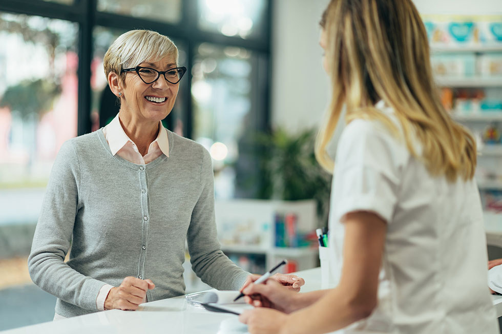 A woman talking to her pharmacist about her 2027 Medicare prescription plan coverage.