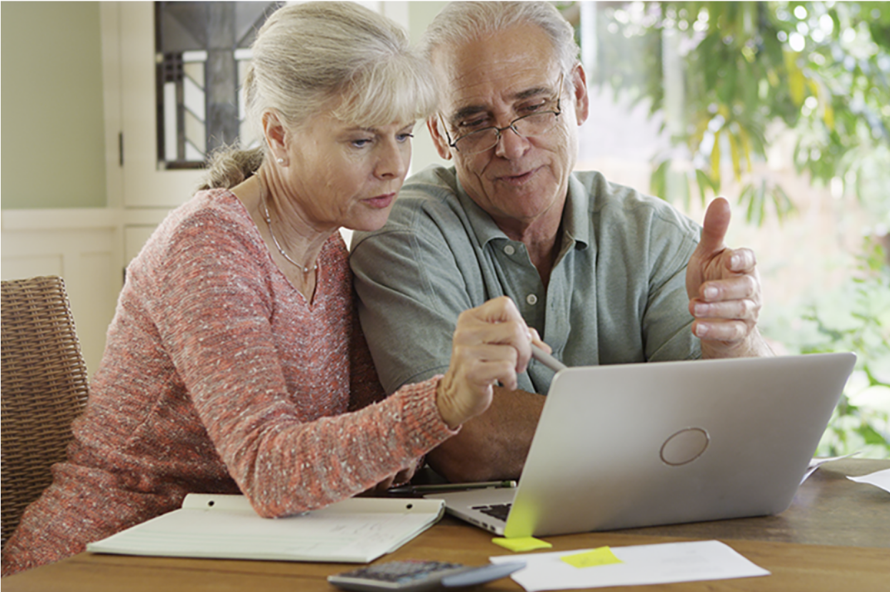 A senior couple in their Florida home on a laptop changing Medicare coverage during the Medicare annual enrollment period