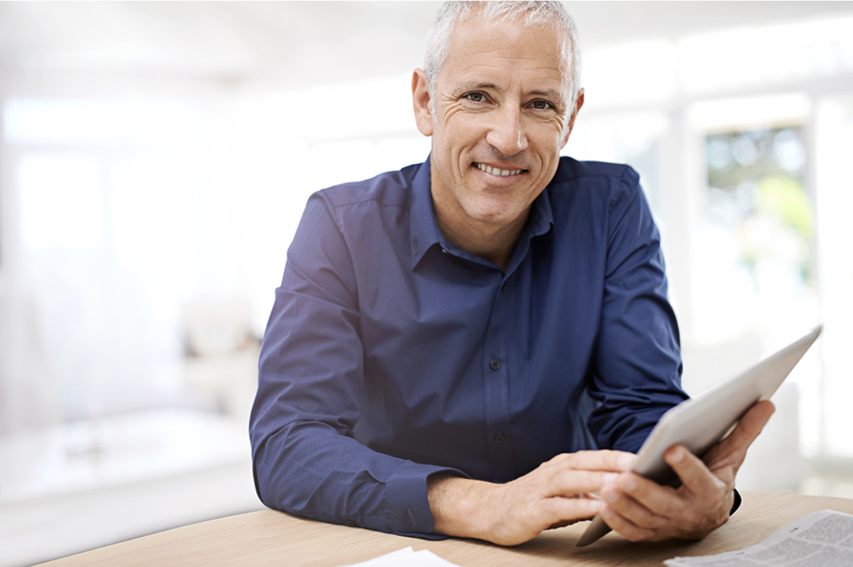 A man at home on his tablet is signing up for Medicare with Absolute Best Insurance