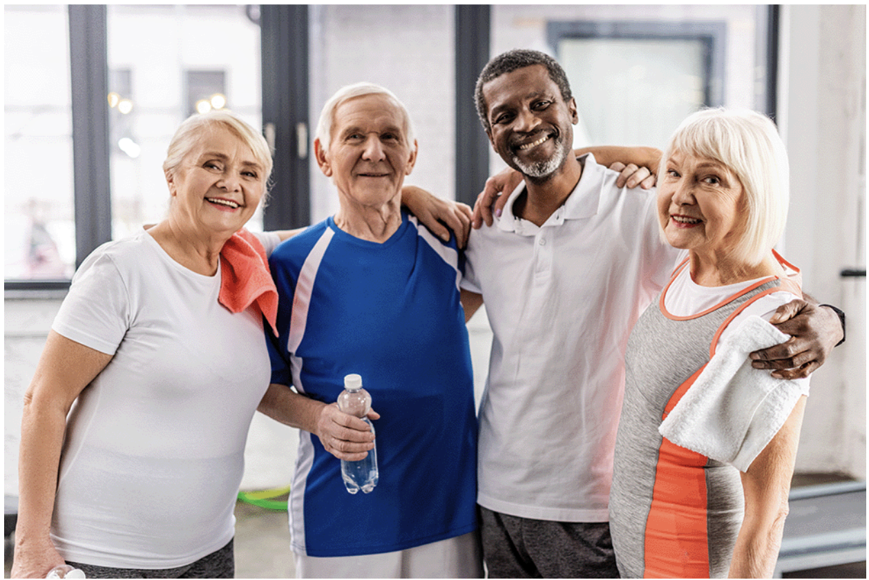 a group of seniors at the gym standing in a group with arms around each other.