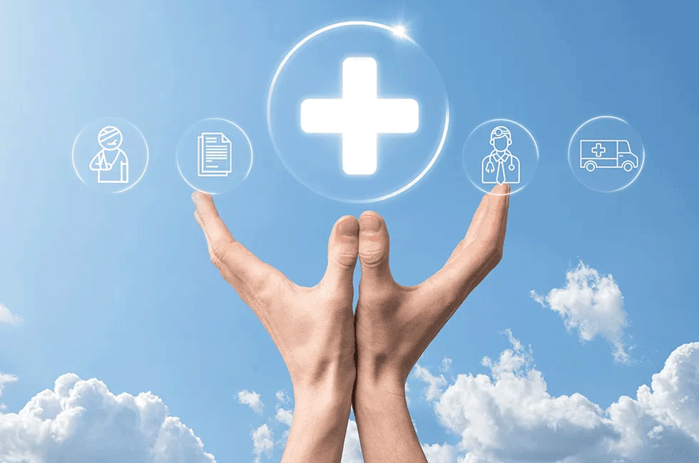 A pair of hands holding up health insurance icons with a blue sky background.